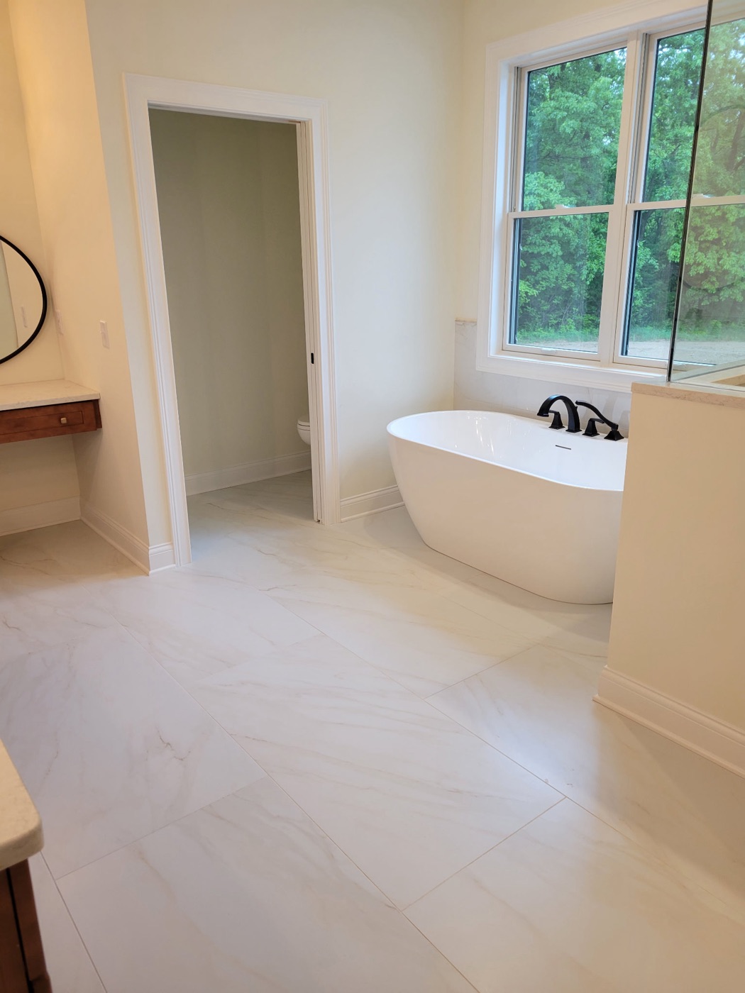 Large-format marble-look tile bathroom floor with freestanding tub