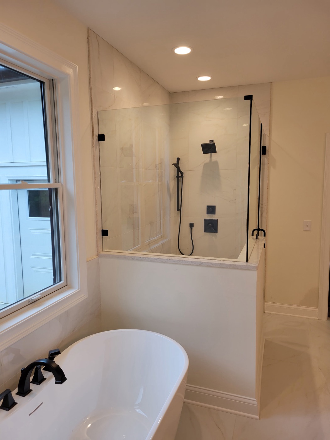 Marble walk-in shower beside a freestanding tub