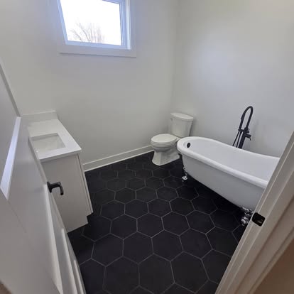 Black hexagon tile floor with freestanding tub